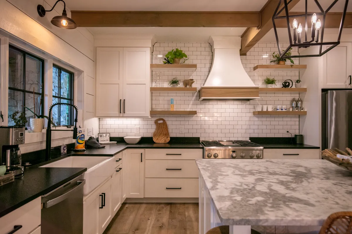 A warm, inviting kitchen featuring a granite island, stainless steel appliances, open shelving, and decorative lighting. The setup is ready for both gourmet cooking and casual snacks, with the island inviting family and friends to gather around.